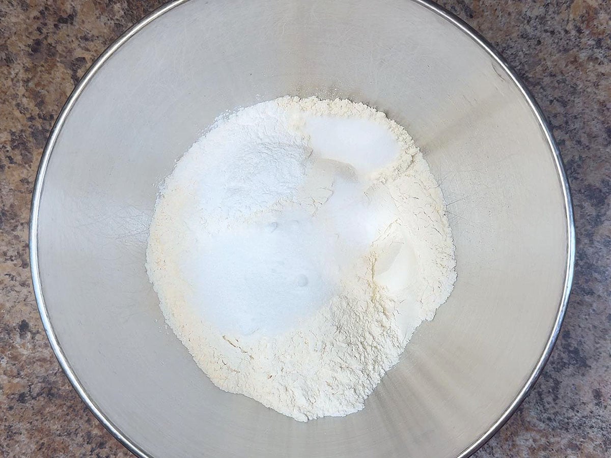 Flour, sugar, baking soda, baking powder and salt in a metal mixing bowl.