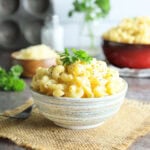 Dish of creamy mac and cheese garnished with pepper and parsley.