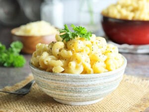 Dish of creamy mac and cheese garnished with pepper and parsley.