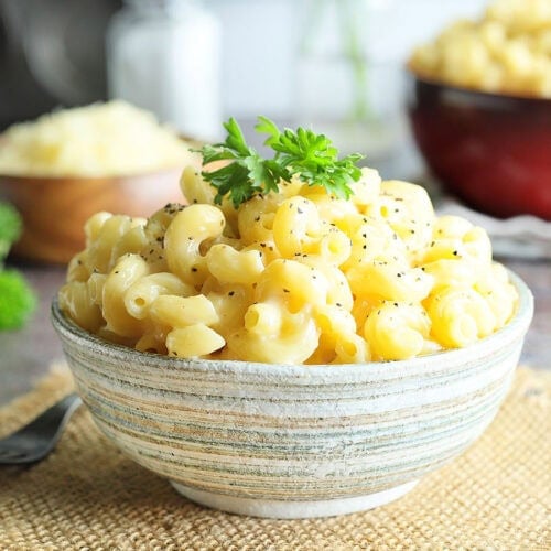 Dish of creamy mac and cheese garnished with pepper and parsley.