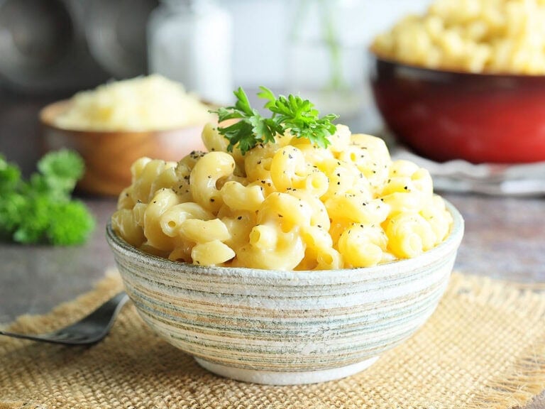 Dish of creamy mac and cheese garnished with pepper and parsley.