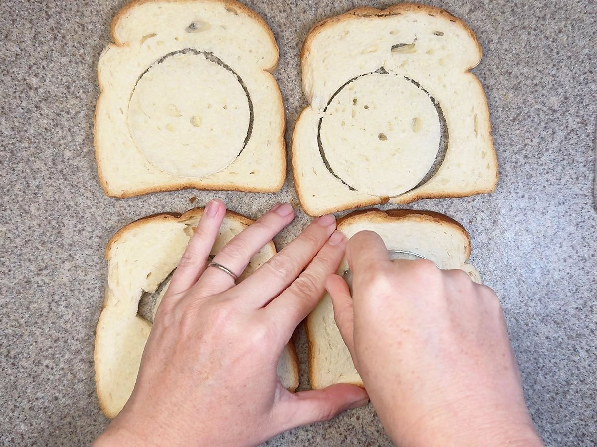 Using a biscuit cutter to cut the white bread into circles.