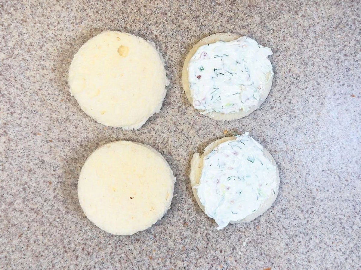 Topping white bread cut into rounds with the cream cheese mixture and topping them with a second bread round.
