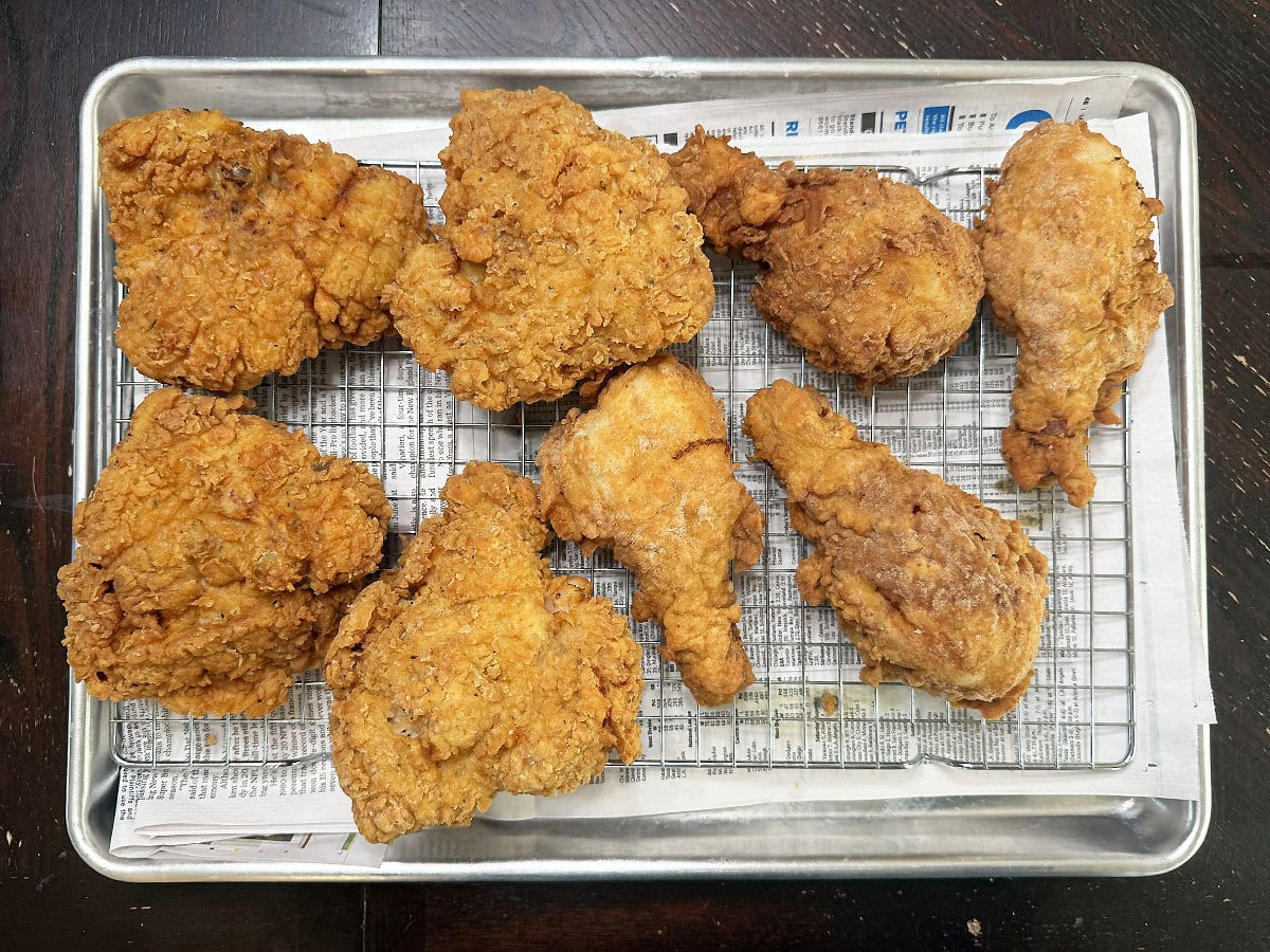 Fried chicken draining on a rack over a layer of paper towels.