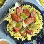 Smoked sausage dinner served over egg noodles in serving bowl.