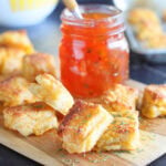 Cheese dreams garnished with dried thyme on a cutting board with a jar of pepper jelly.