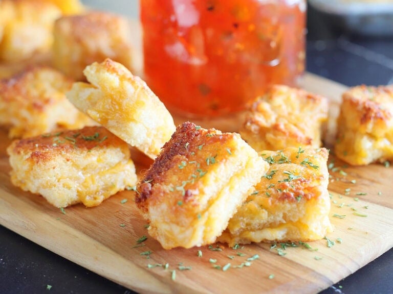 Cheese dreams garnished with dried thyme on a cutting board with a jar of pepper jelly.