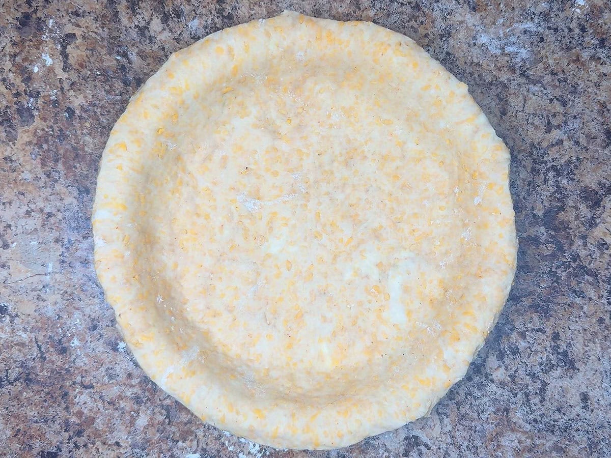 First pie crust fitted into a pie plate and the edges trimmed.