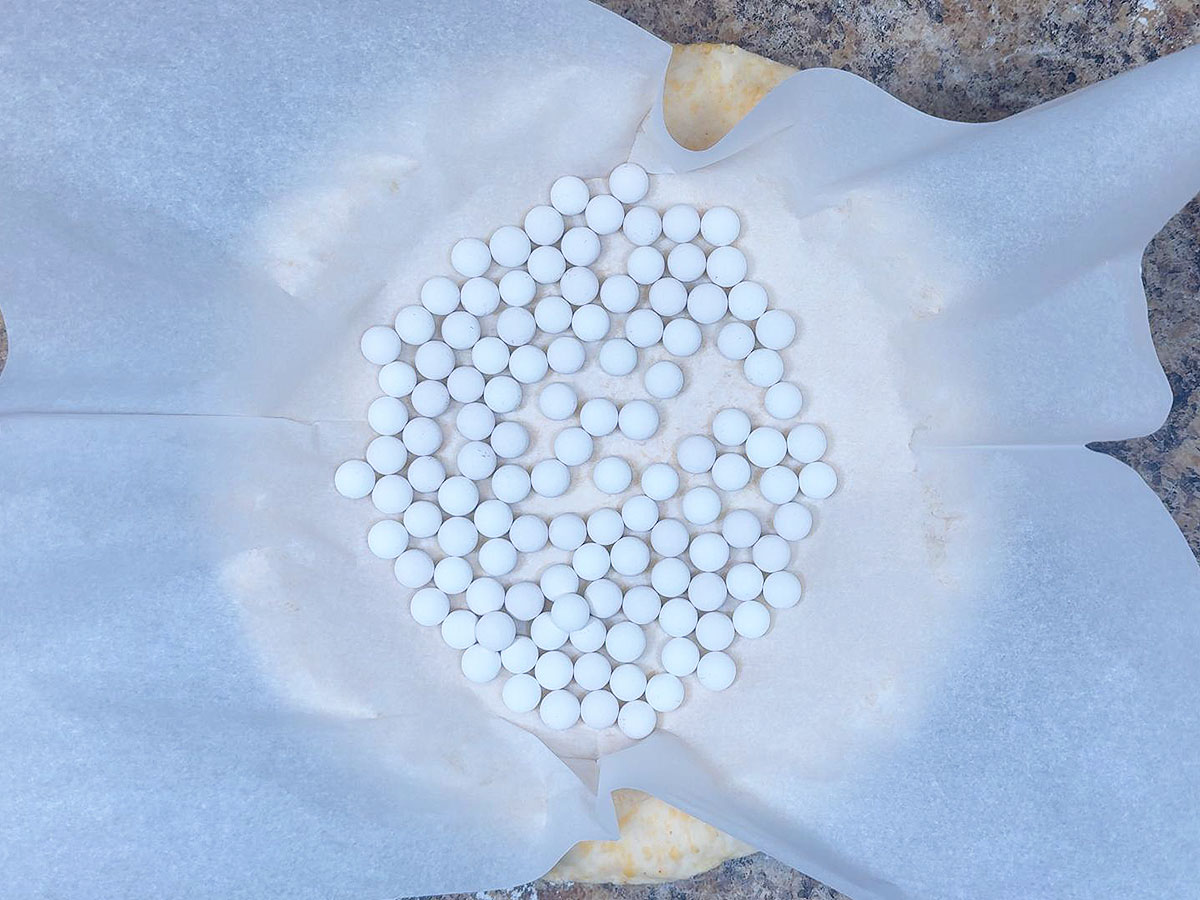 Pie crust lined with parchment paper and pie weights.