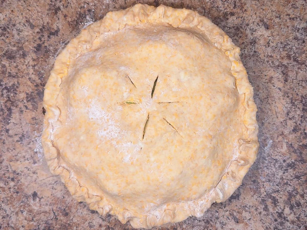 Granny Smith apple pie with the second pie crust fitted over the top and slits cut into the crust.