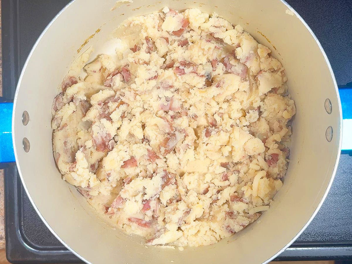Cooked potatoes in a stock pot after they have been mashed.