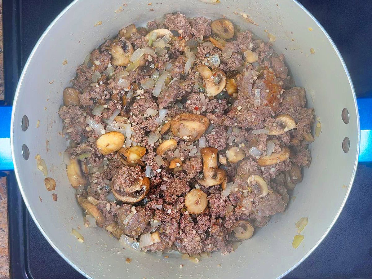 Sausage, sirloin, onion, garlic and mushrooms browned in a large stockpot.