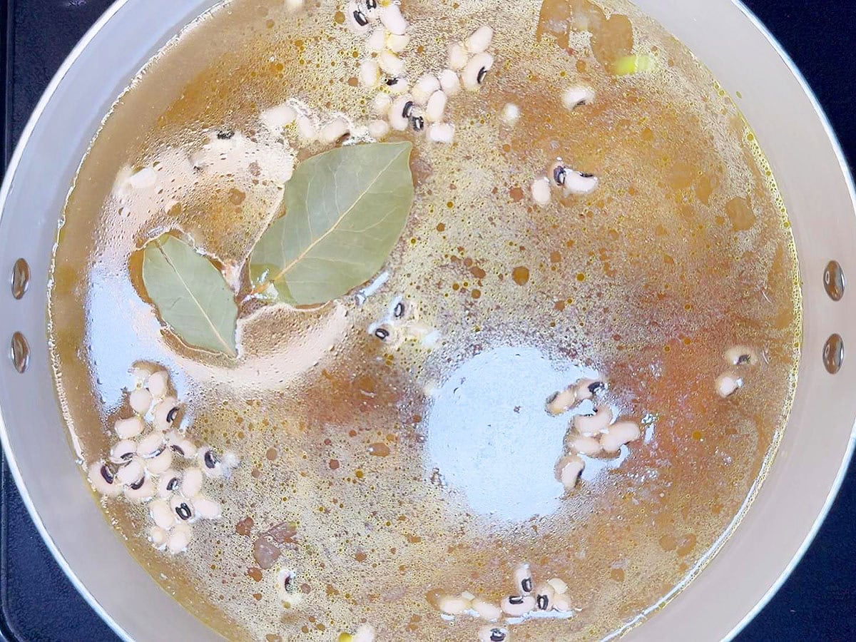 Two bay leaves floating on top of the chicken broth before simmering the black eyed pea soup.