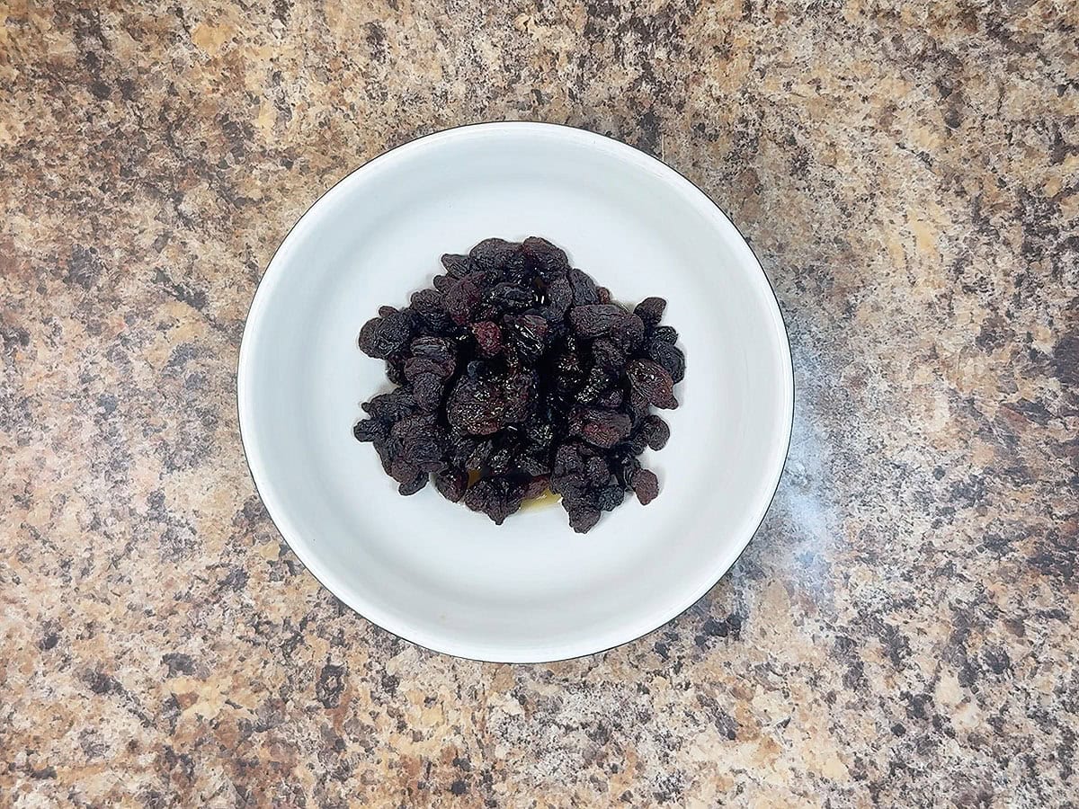 Dish of raisins soaking in apple cider.