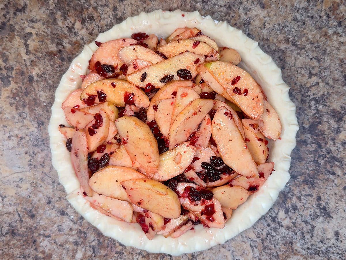 Unbaked pie crust filled with the cranberry apple filling.