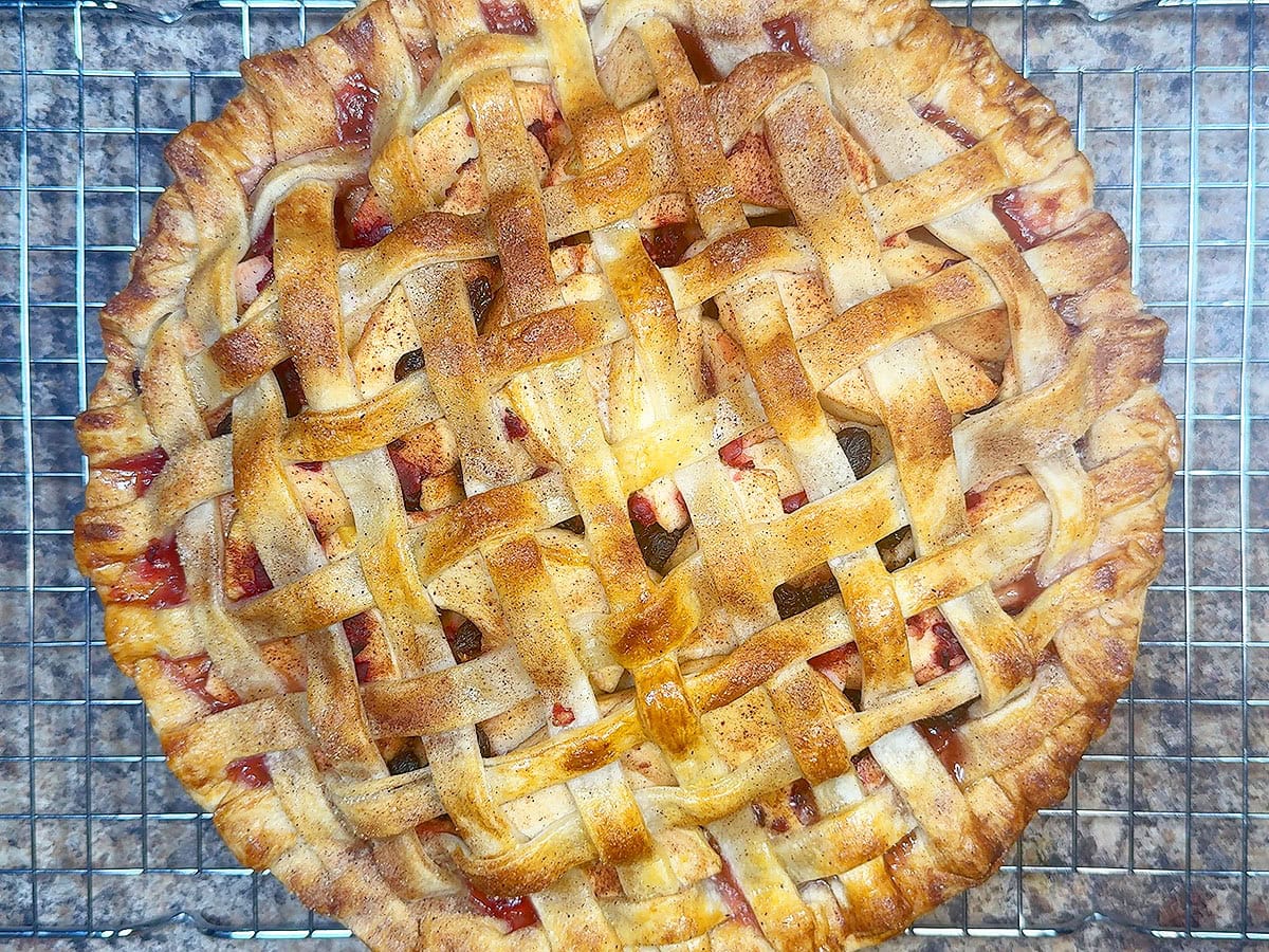 Cranberry apple pie cooling on a wire rack.