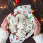 Pair of hands placing an bowl of coconut and cornflake cookies on a holiday table.
