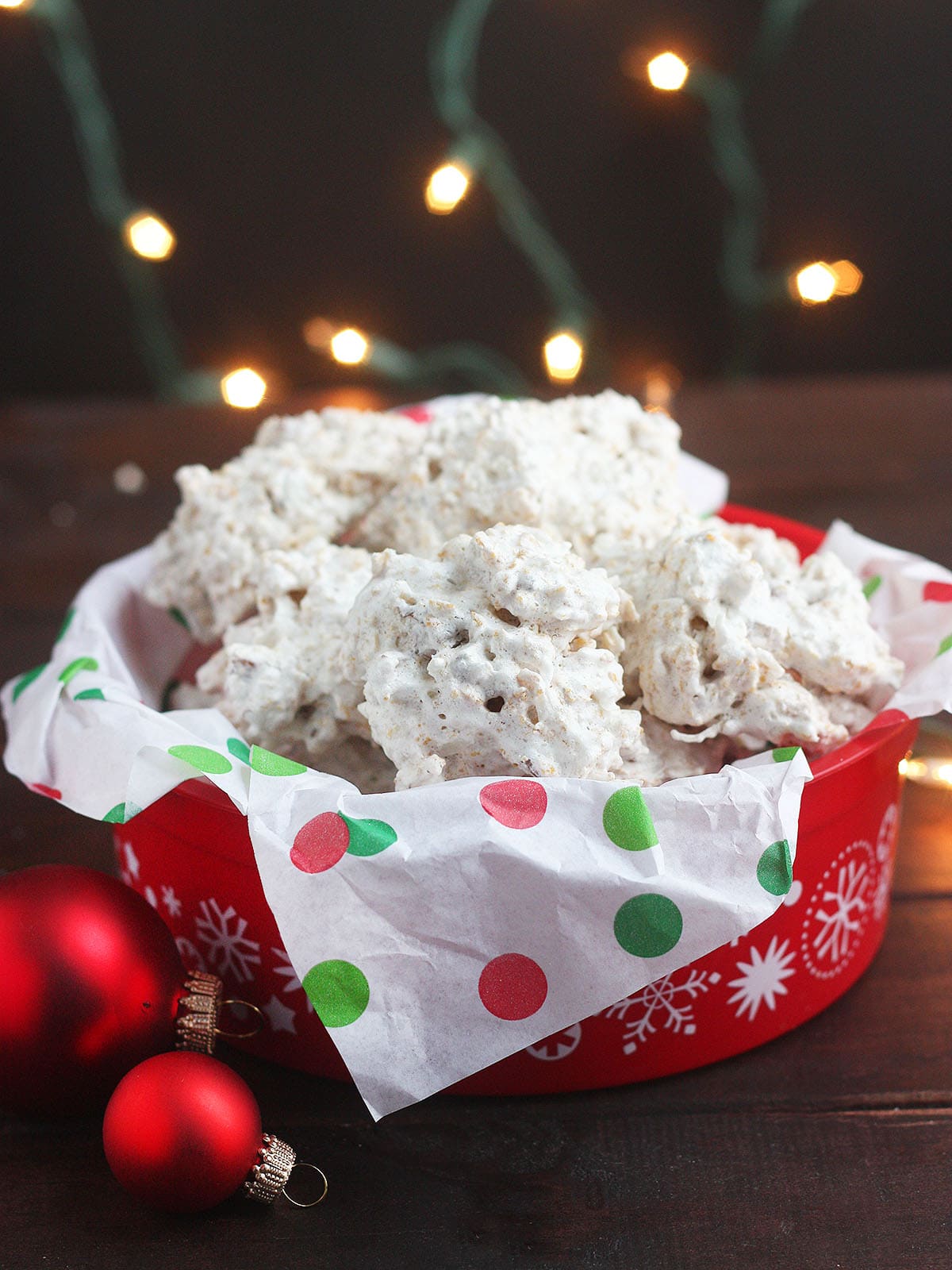 Pile of coconut and cornflake cookies in a red holiday tin lined with Christmas tissue paper.