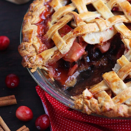 Lattice cranberry apple pie with a slice removed.
