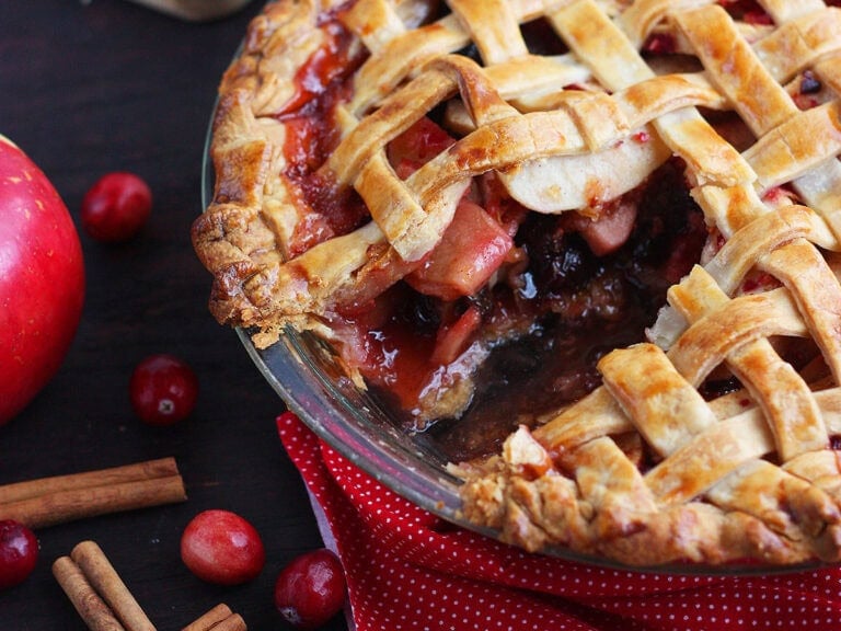 Lattice cranberry apple pie with a slice removed.