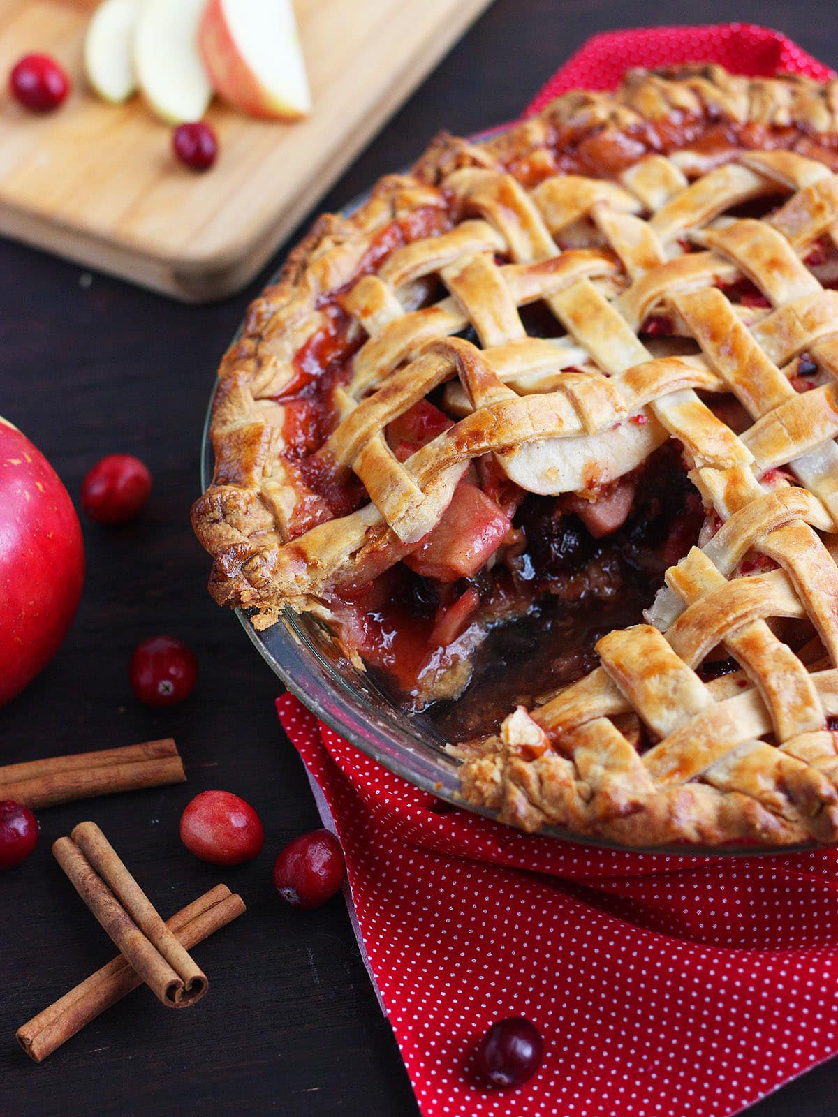 Lattice cranberry apple pie with a slice removed.