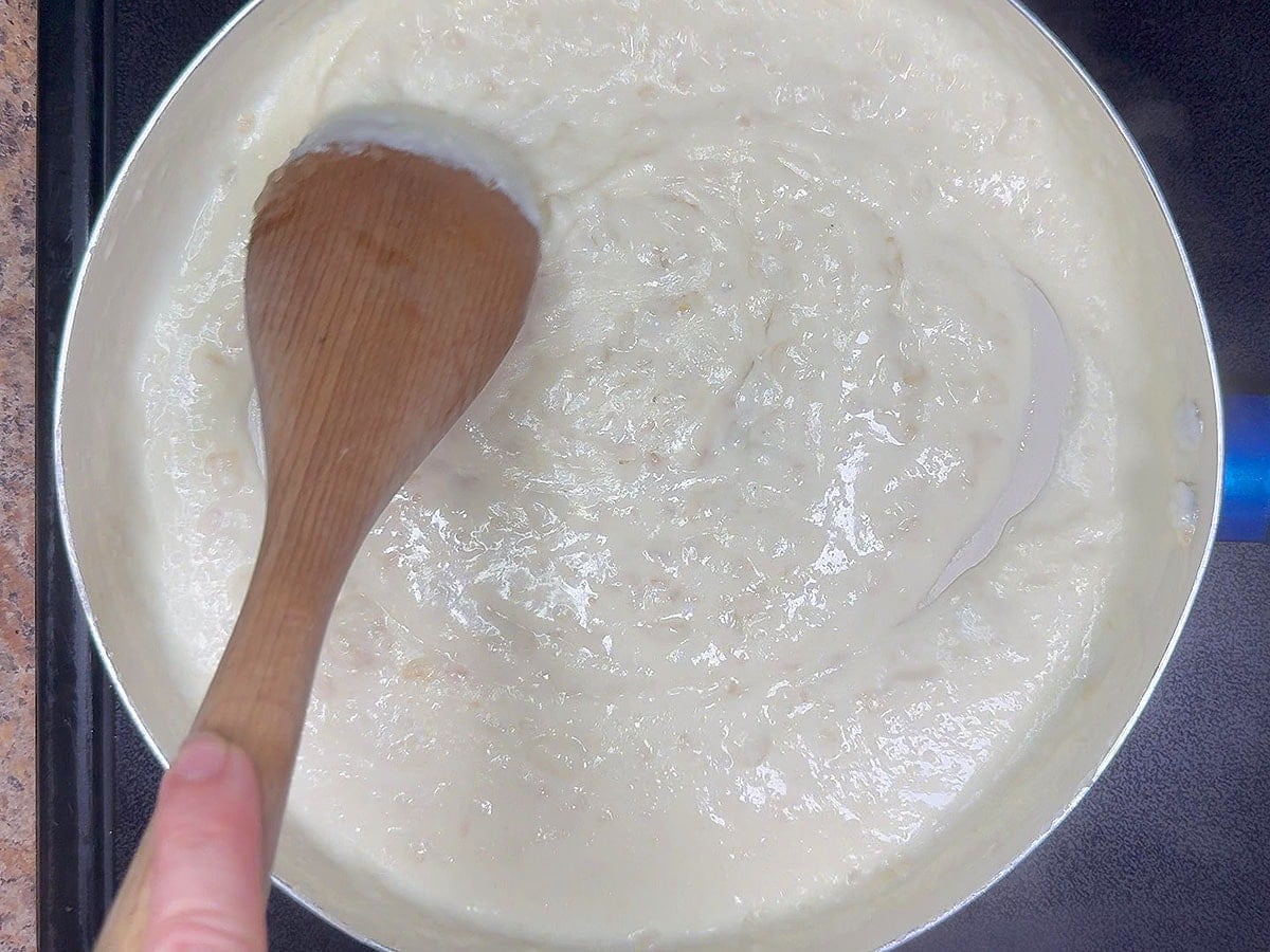 Stirring the cream sauce until thickened.